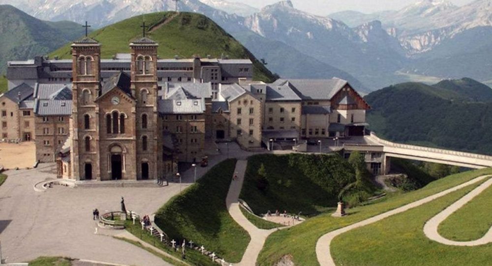 Sanktuarium La Salette w górach, widok z lotu ptaka na kościół i zabudowania otoczone alpejskimi szczytami